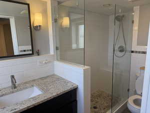 Bathroom featuring a shower stall, vanity, and backsplash
