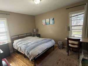 Bedroom featuring multiple windows, light wood finished floors, and a textured ceiling