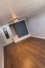 Additional living space featuring dark wood-type flooring and baseboards