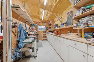 Miscellaneous room with concrete floors, a workshop area, and lofted ceiling