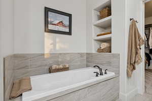 Bathroom featuring built in features, a garden tub, and a walk in closet