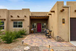 Property entrance with a patio, stucco siding, and a garage