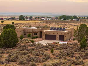 Southwest-style home featuring solar panels, stucco siding, view of desert landscape, and a view of rural / pastoral area
