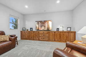 Living area with light carpet and recessed lighting