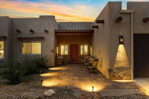 Property entrance featuring a patio area, stucco siding, and stone siding