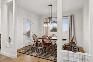 Dining space featuring light wood-style floors, healthy amount of natural light, and a chandelier