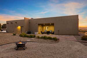Rear view of house with a patio, stucco siding, and a fire pit