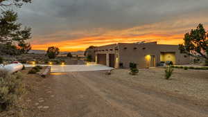 Pueblo-style house with concrete driveway, an attached garage, and stucco siding