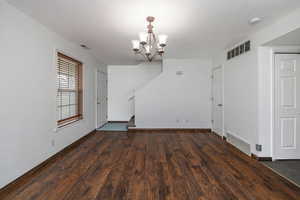Unfurnished dining area with a chandelier and dark wood-style floors