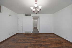 Unfurnished dining area with hanging lights and dark wood-type flooring