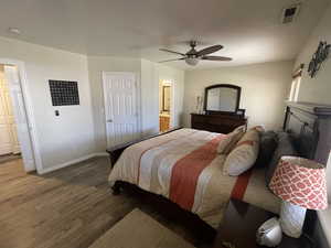 Bedroom featuring dark wood finished floors, ceiling fan, and connected bathroom