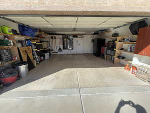 Garage with freestanding refrigerator, heating unit, and gas water heater