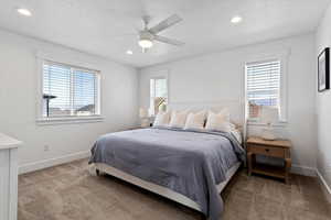 Bedroom with light carpet, a ceiling fan, multiple windows, and recessed lighting