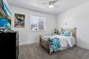 Carpeted bedroom with a ceiling fan and a textured ceiling