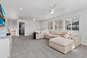Living area with light carpet, ceiling fan, and recessed lighting