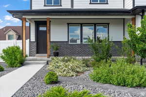 Property entrance featuring brick siding and covered porch
