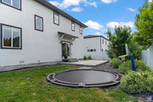 Rear view of house featuring a patio, stucco siding, and a trampoline