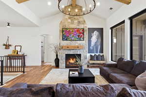 Living area featuring beamed ceiling, wood finished floors, a fireplace, arched walkways, and a chandelier