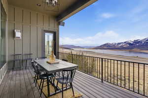 Deck with outdoor dining area and a water and mountain view