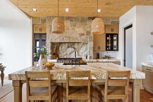 Kitchen featuring light stone counters, light wood finished floors, light wood finish cabinets, a breakfast bar area, and wood ceiling