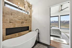 Ensuite bathroom with healthy amount of natural light, a freestanding bath, a mountain view, and ceiling fan