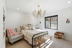 Bedroom with light colored carpet and suspended lighting