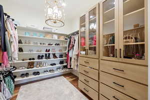 Walk in closet with a chandelier and light wood-type flooring