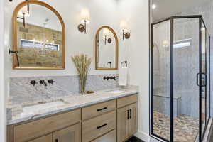 Full bathroom featuring double vanity, a shower stall, and backsplash