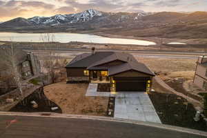 View of front facade featuring board and batten siding, a mountain view, concrete driveway, stone siding, and roof with shingles