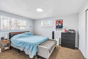Carpeted bedroom with a textured ceiling and a closet