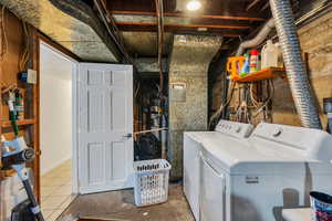 Laundry area with washer and clothes dryer, water heater, and unfinished concrete floors