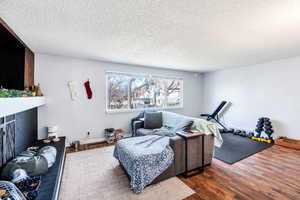 Exercise room featuring wood finished floors, a fireplace, and a textured ceiling