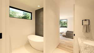 Ensuite bathroom with vanity, healthy amount of natural light, a freestanding tub, recessed lighting, and light wood-style flooring