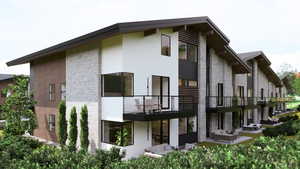 Rear view of house with stone siding, a balcony, and stucco siding