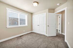Unfurnished bedroom with dark carpet and a closet