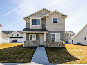 Craftsman house with board and batten siding, stone siding, and a front lawn