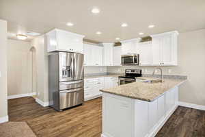 Kitchen with stainless steel appliances, arched walkways, a peninsula, white cabinetry, and recessed lighting
