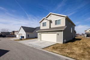 View of front of property featuring board and batten siding, an attached garage, concrete driveway, a residential view, and a front yard