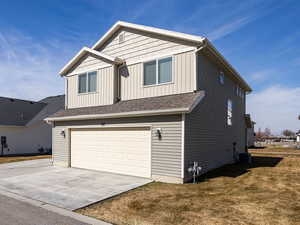 View of front of property featuring board and batten siding, an attached garage, concrete driveway, a residential view, and a front yard