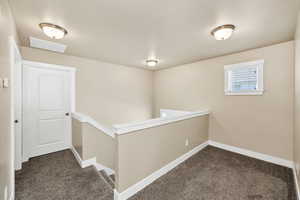 Hallway featuring dark colored carpet and an upstairs landing