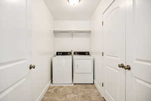 Laundry area featuring washing machine and clothes dryer and stone finish floors