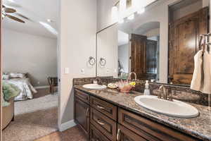 Ensuite bathroom with double vanity, ceiling fan, and light carpet