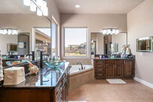 Bathroom featuring two vanities, a bath, and recessed lighting