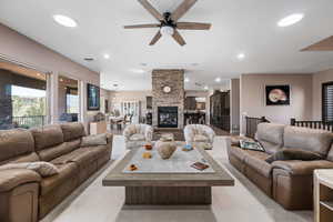 Living room featuring ceiling fan, a stone fireplace, and recessed lighting