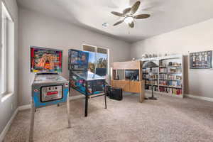Game room with a ceiling fan, light carpet, and a desk