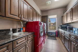 Laundry area featuring washing machine and clothes dryer, dark tile patterned flooring, and cabinet space