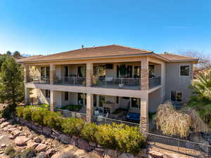 Rear view of house featuring stucco siding, a fenced backyard, a balcony, a tiled roof, and a patio area