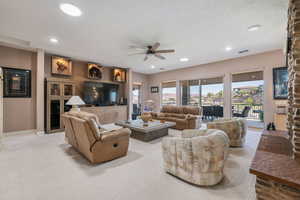 Living room with a ceiling fan, recessed lighting, and light colored carpet