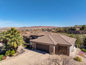 View of front of house with stone siding, an attached garage, stucco siding, and concrete driveway