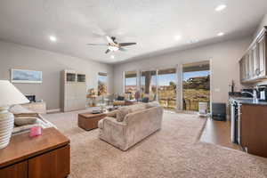 Living room with light carpet, ceiling fan, and recessed lighting